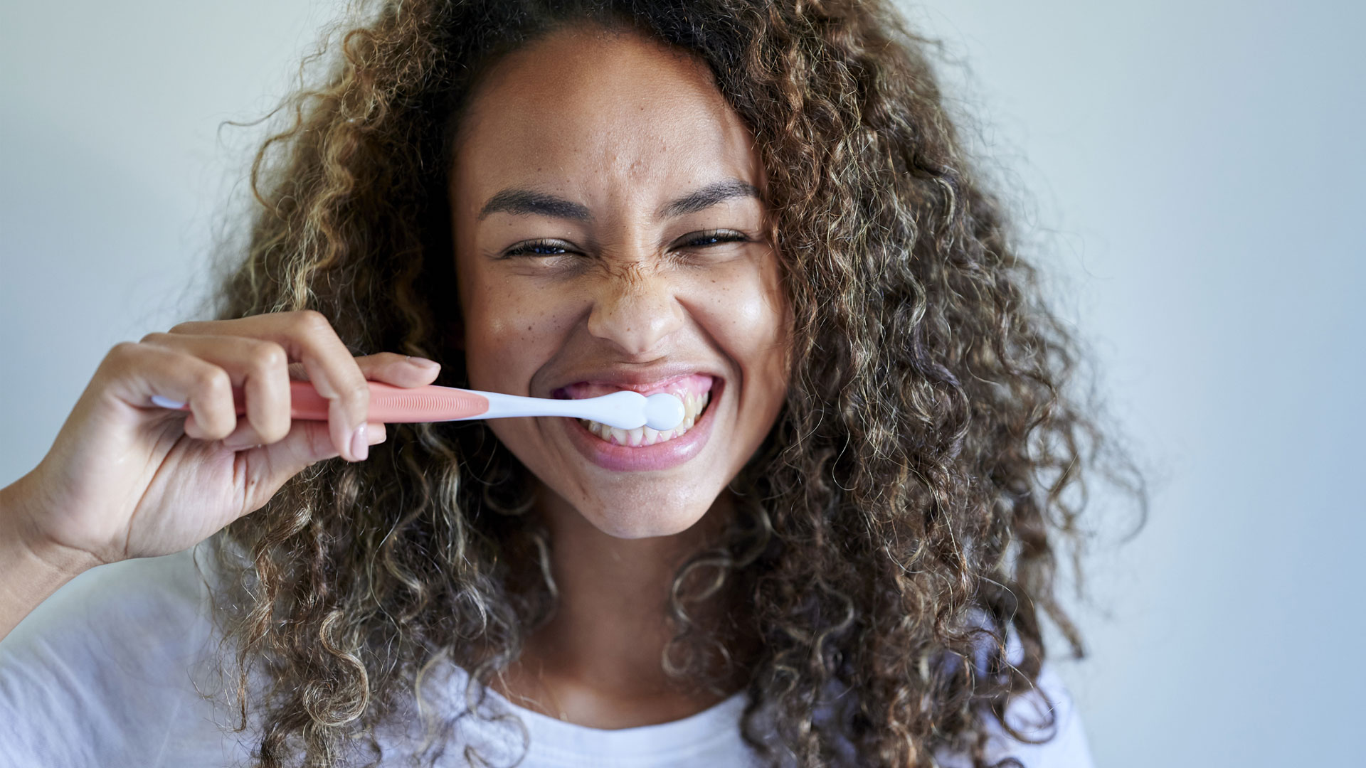 How Many Teeth Do Humans Have? image shows woman brushing teeth