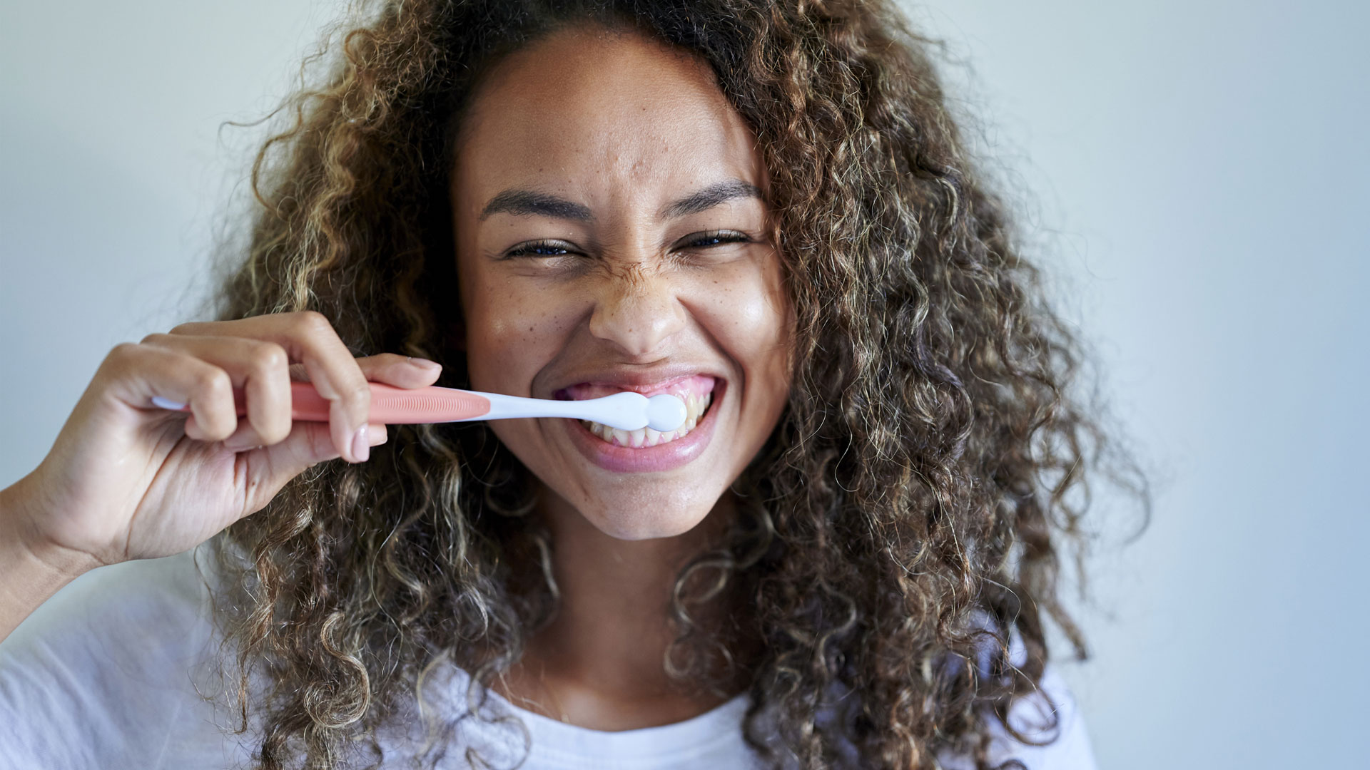 ¿Cuántos dientes tienen los humanos?  la imagen muestra a una mujer cepillándose los dientes