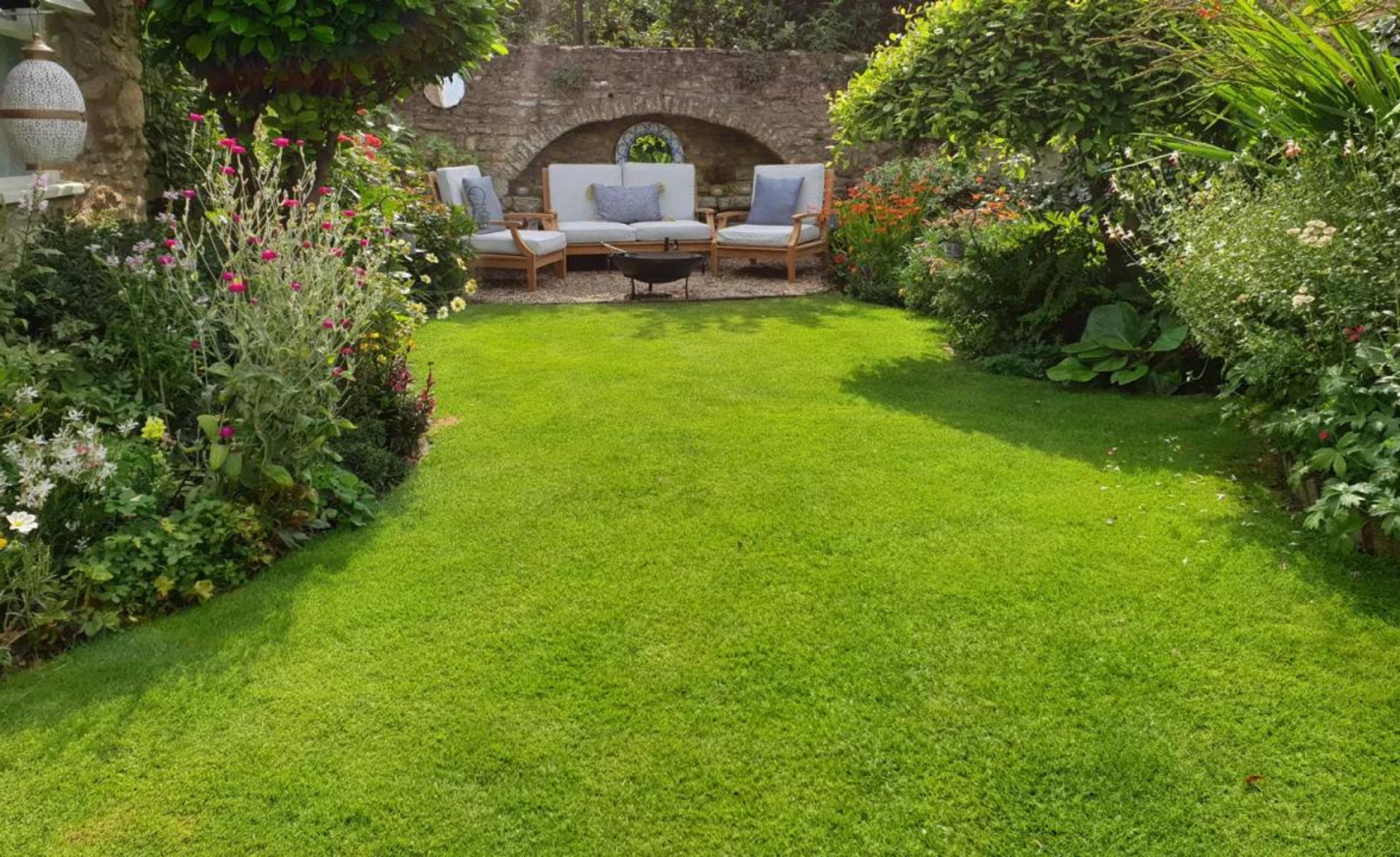 Rumput hijau muda dengan furnitur taman di latar belakang