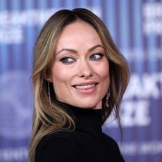 Olivia Wilde looking away from the camera wearing a black turtleneck 