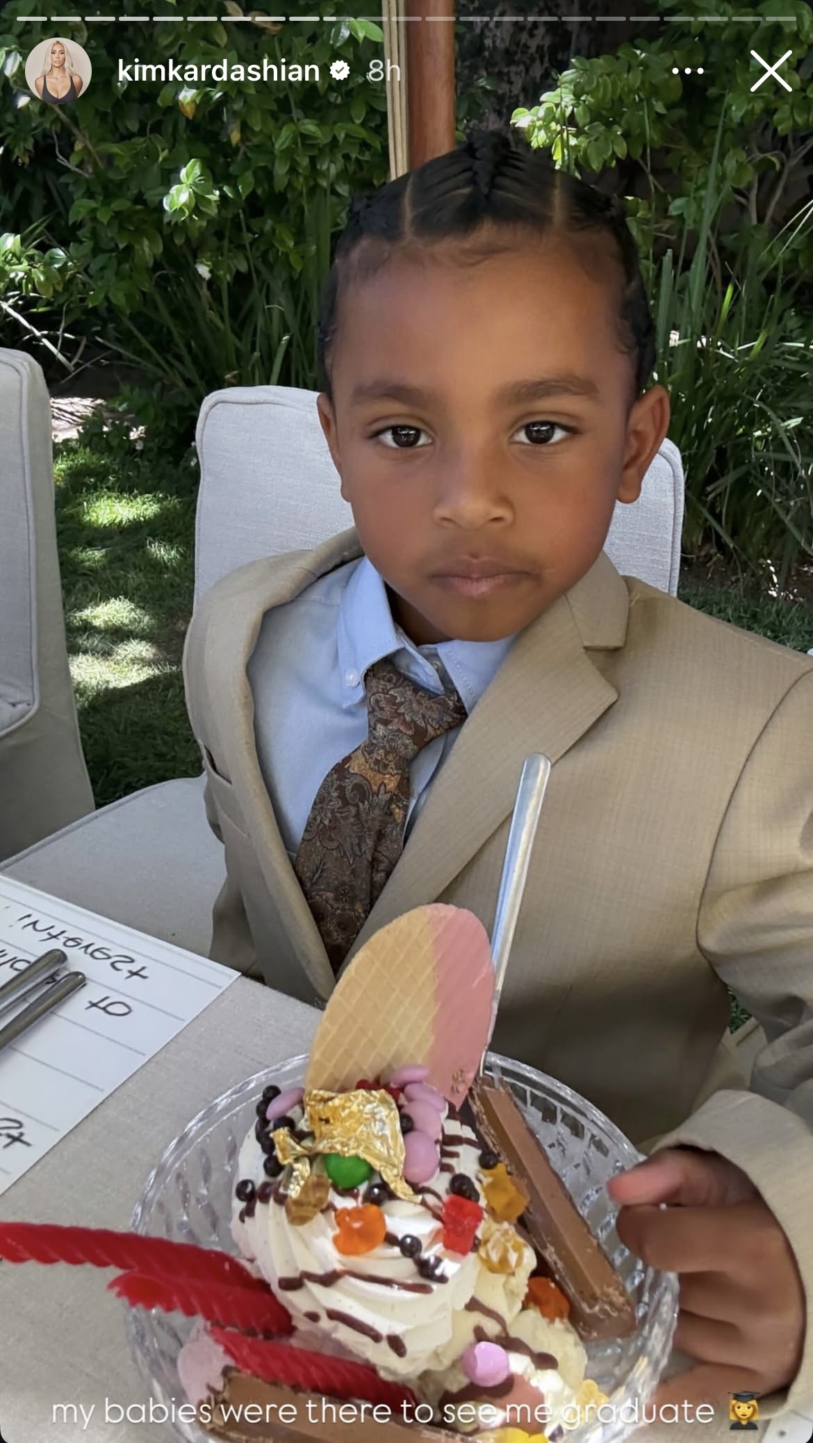 Psalm West is shown in a suit with a briefcase in photos from Kim Kardashian's Instagram Stories celebrating her graduation from lawschool.