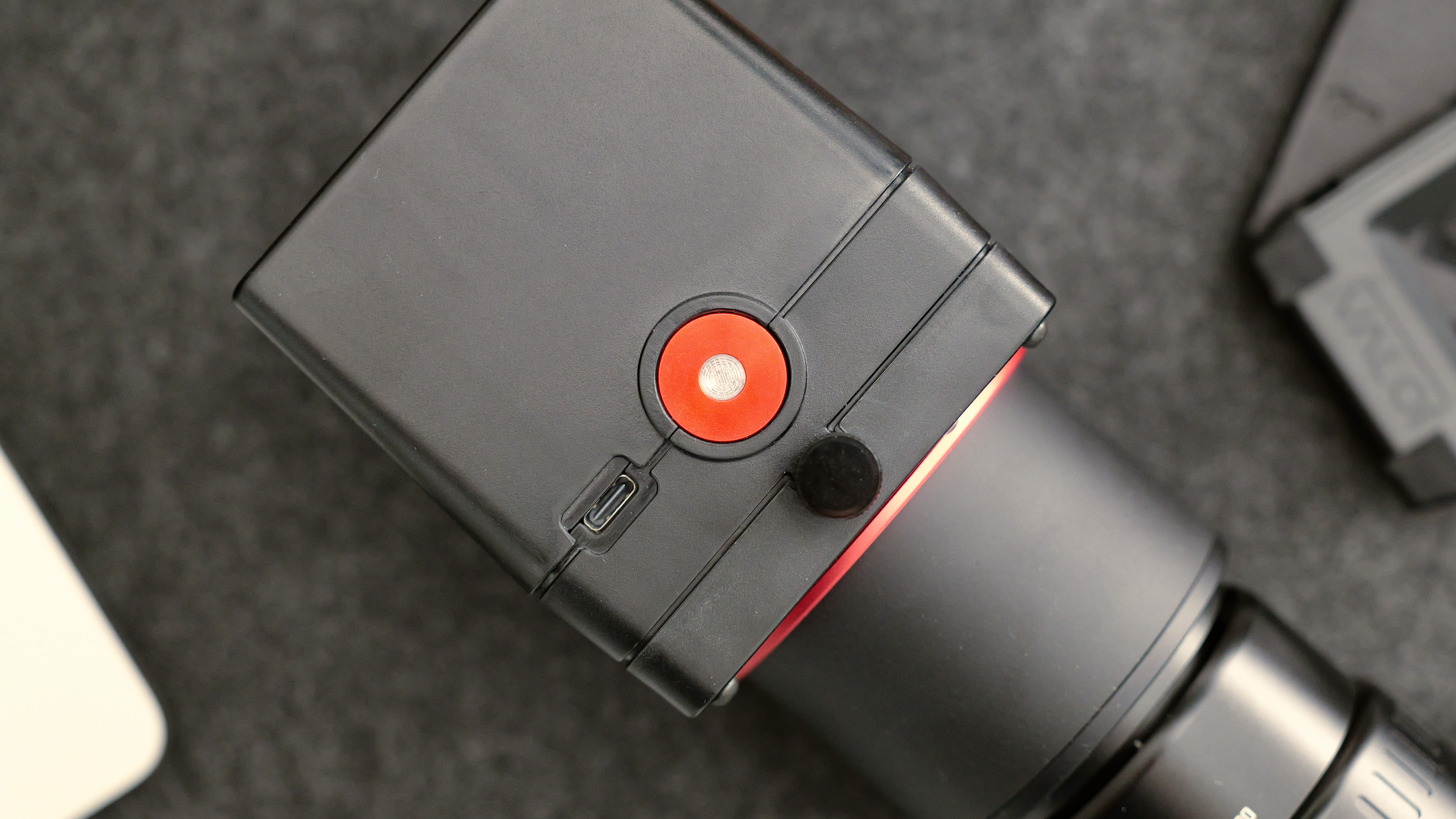 A close-up of the Valoi easy35 V2 film scanning unit showing the red button, USB-C port, and lens attachment.