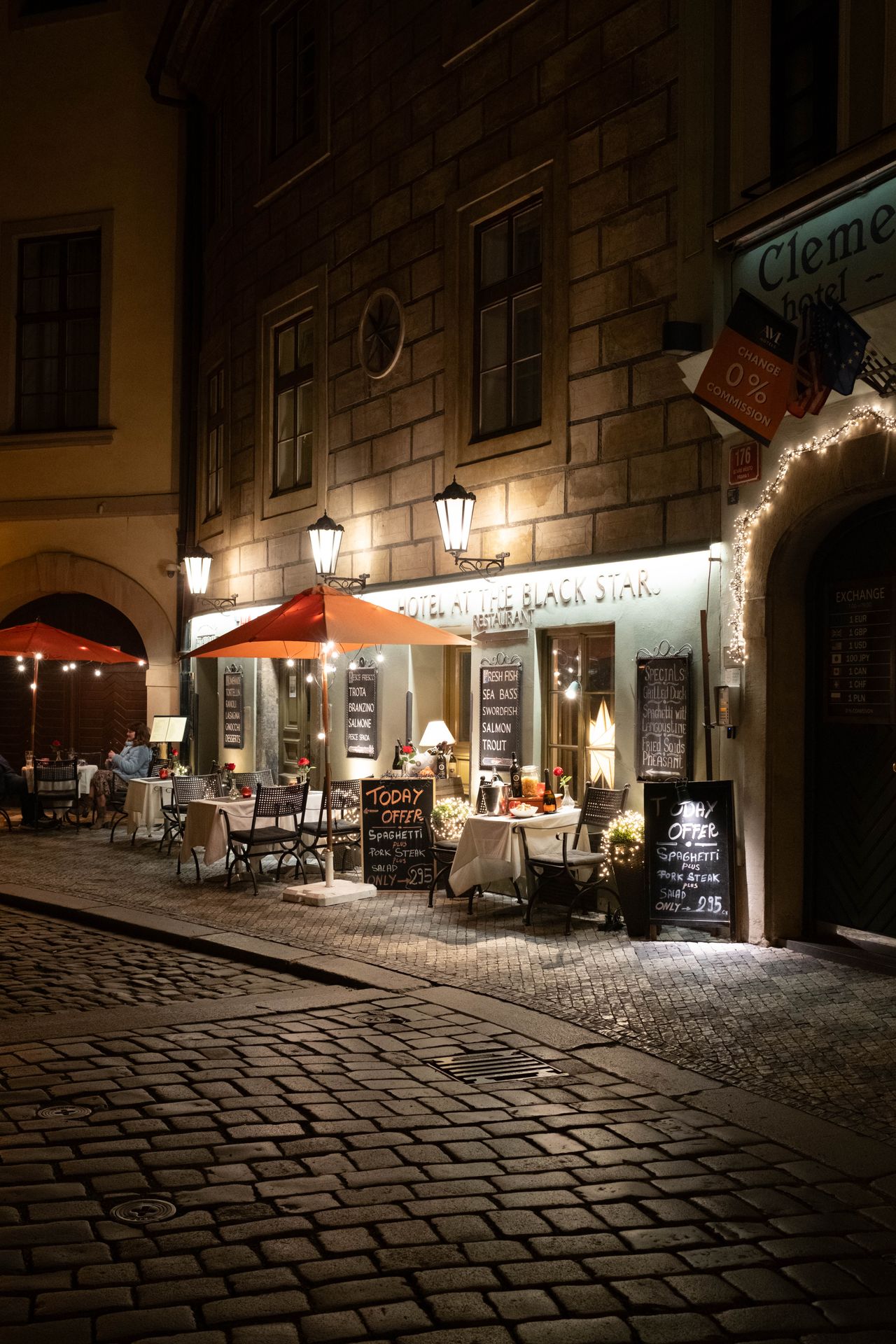 A restaurant in Prague on a cobbled street lit up at night