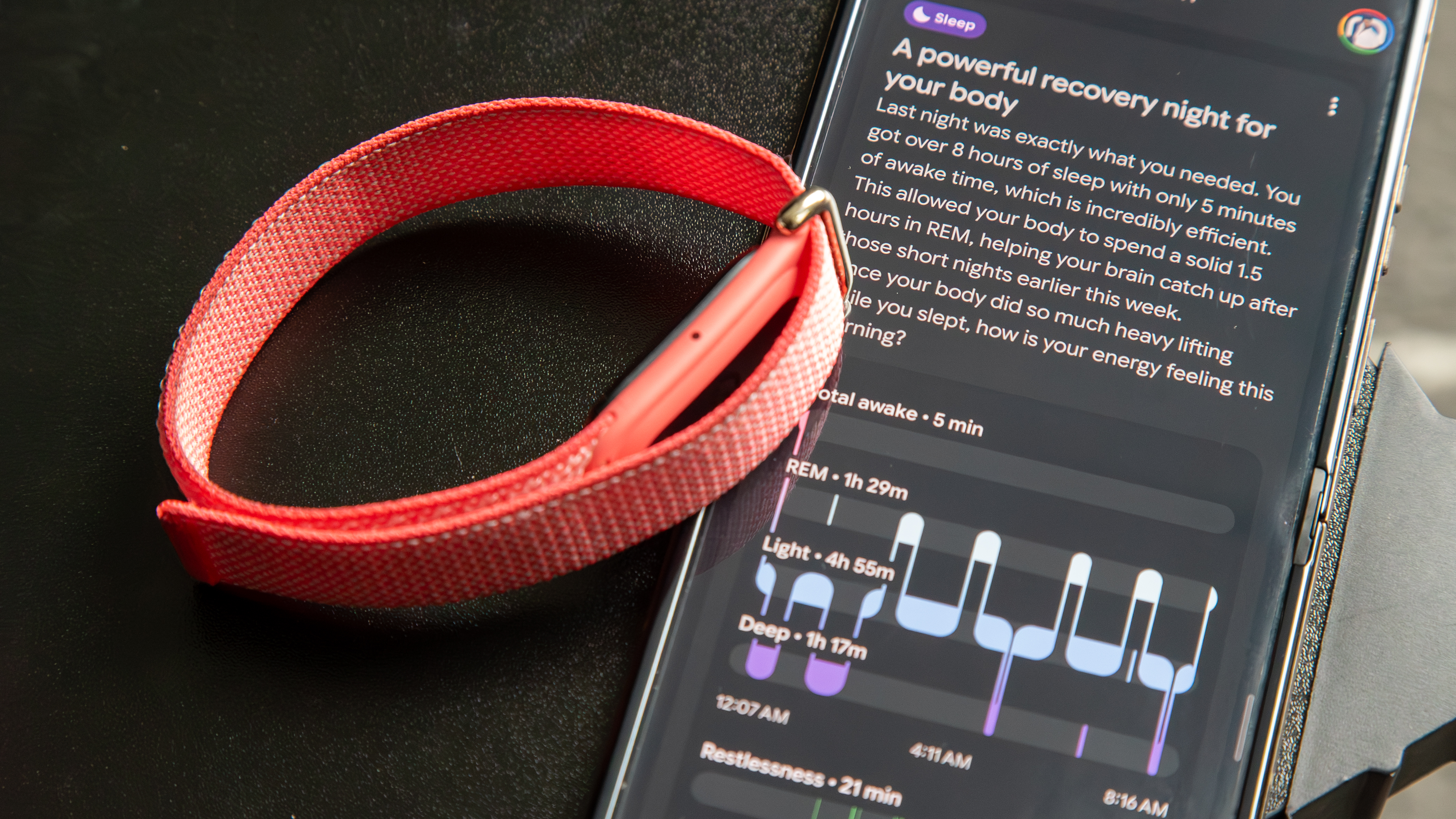 The Fitbit Air next to a smartphone with the Google Health app displaying a sleep analysis