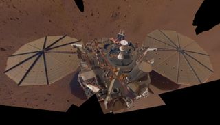 A wide view looking down on a scientific lander probe with two circular solar arrays on its either side.