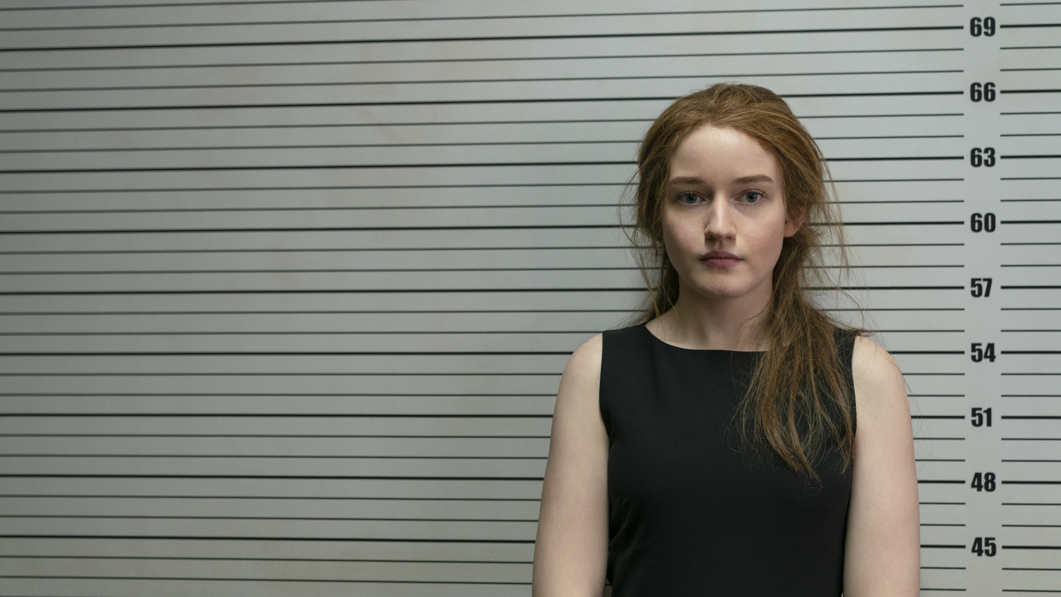 Julia Garner as Anna Delvey, getting her mug shot taken, in Inventing Anna