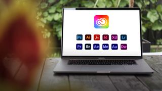 A laptop sits on a tabletop with the icons for the Adobe Creative Cloud All Apps plan on the screen