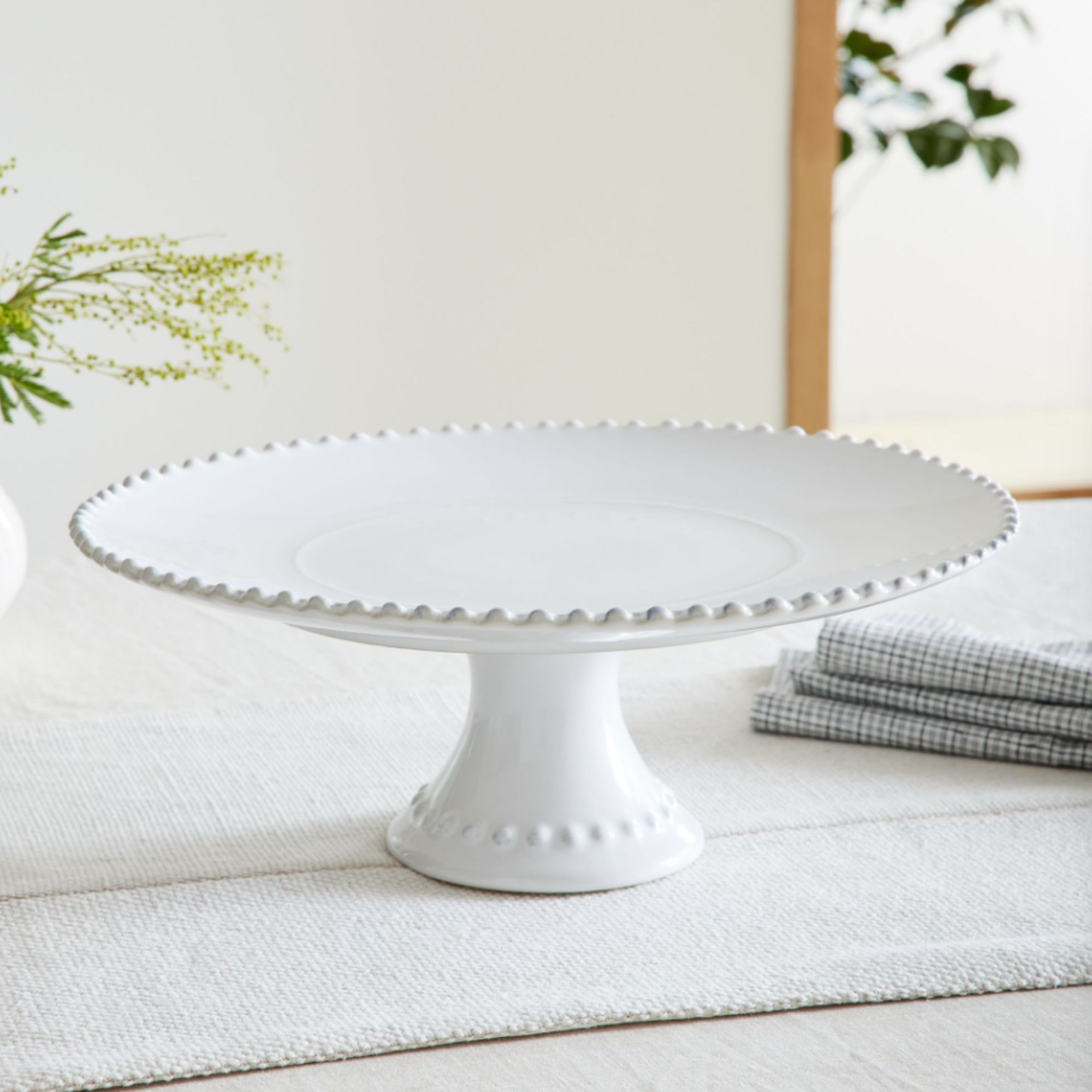 White stoneware cake stand on white tablecloth