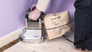 an edge sander being used to sand floorboards