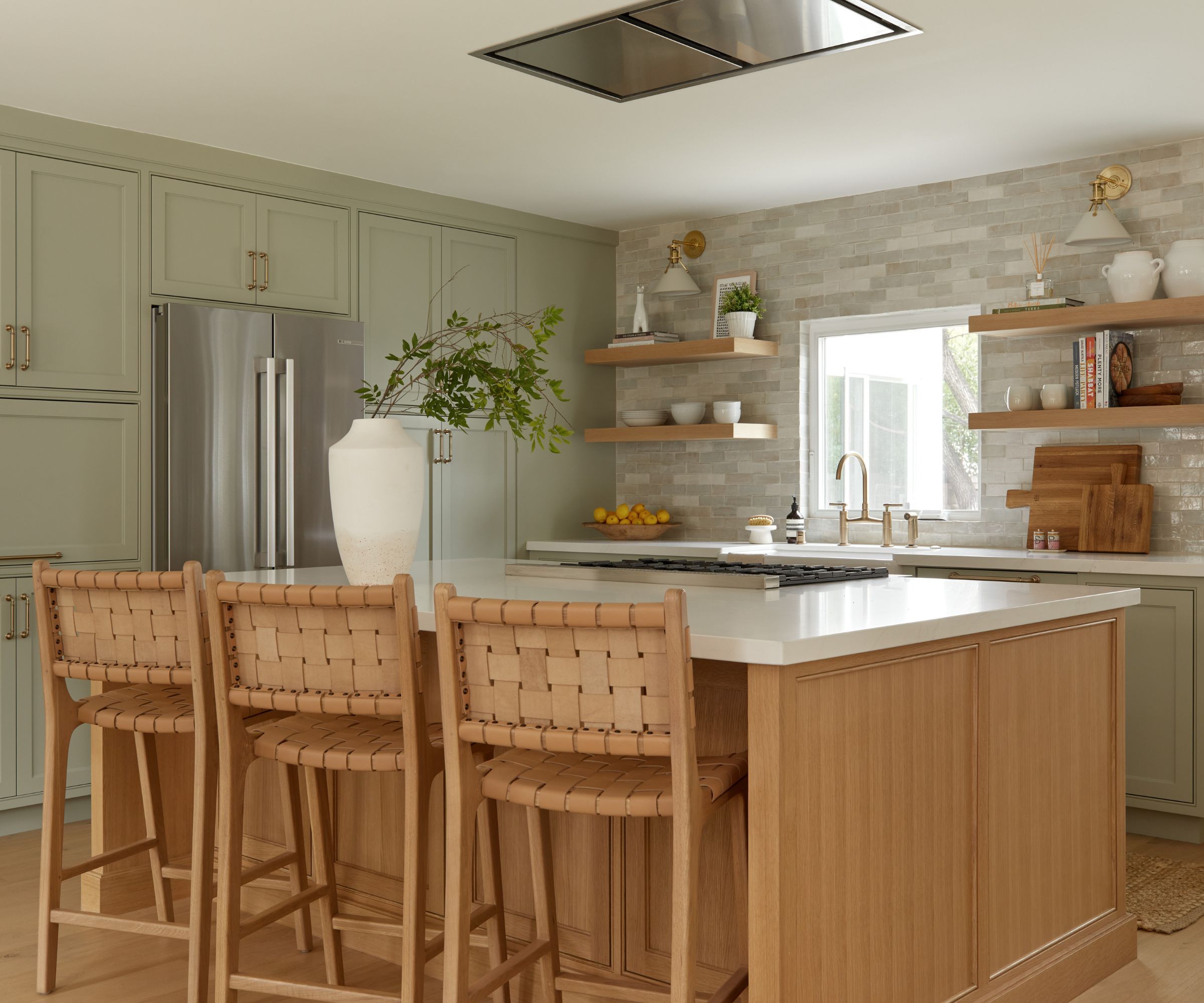 A kitchen with green cabinets, a wooden island, and marble countertops
