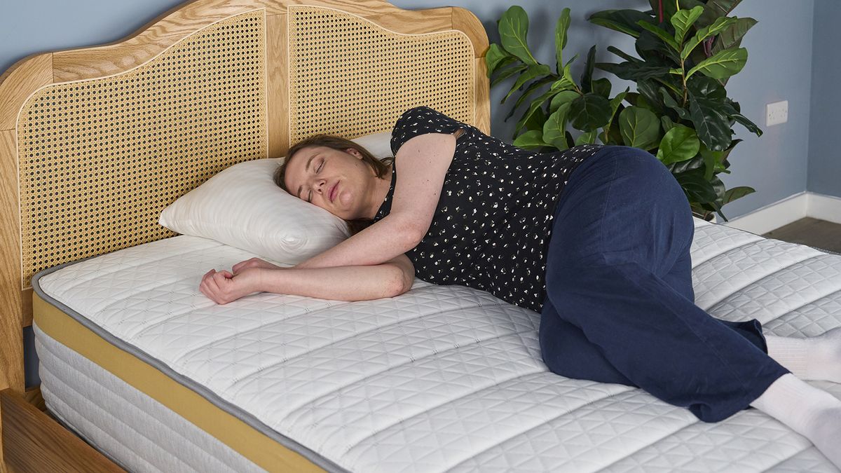 A woman lies on her side on the Helix Dawn Mattress, testing for comfort and support.