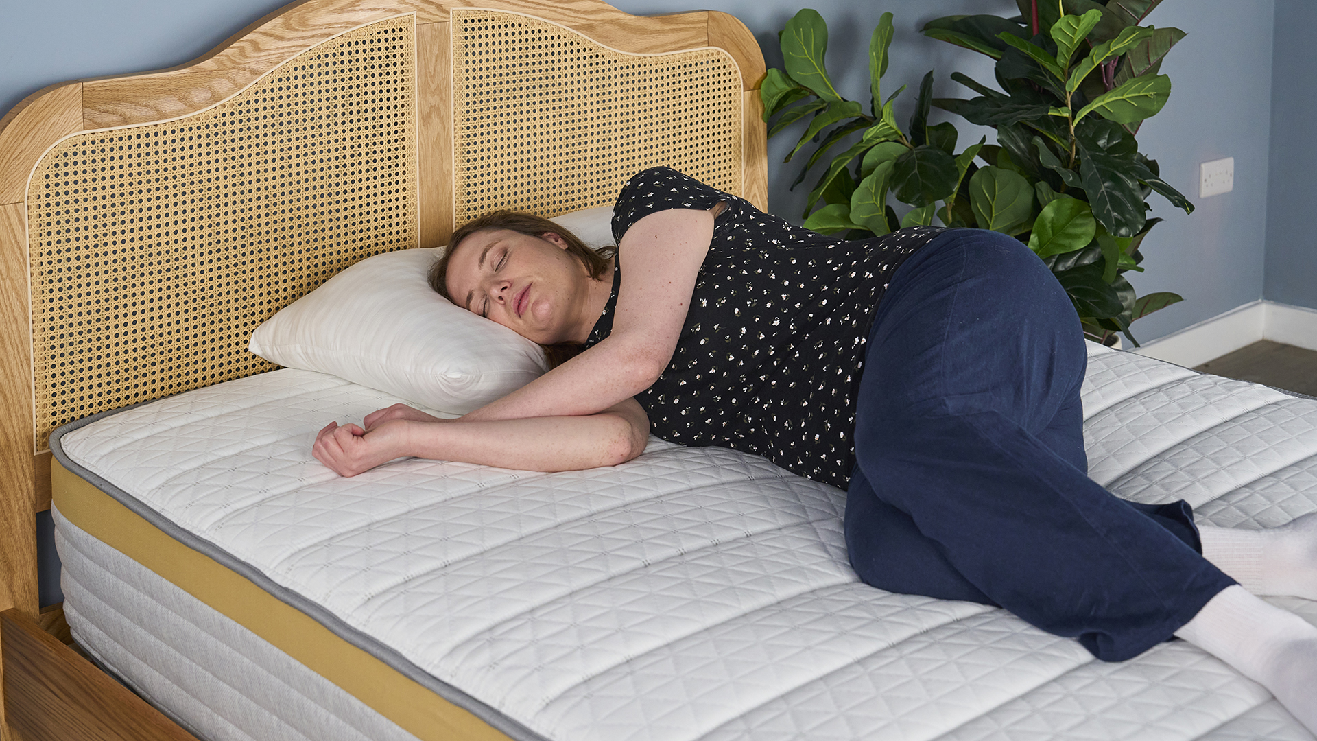 A woman lies on her side on the Helix Dawn Mattress, testing for comfort and support.