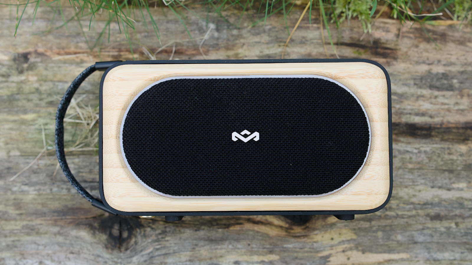 House of Marley Roots Solar Bluetooth speaker outdoors in a garden, on a wooden bench.