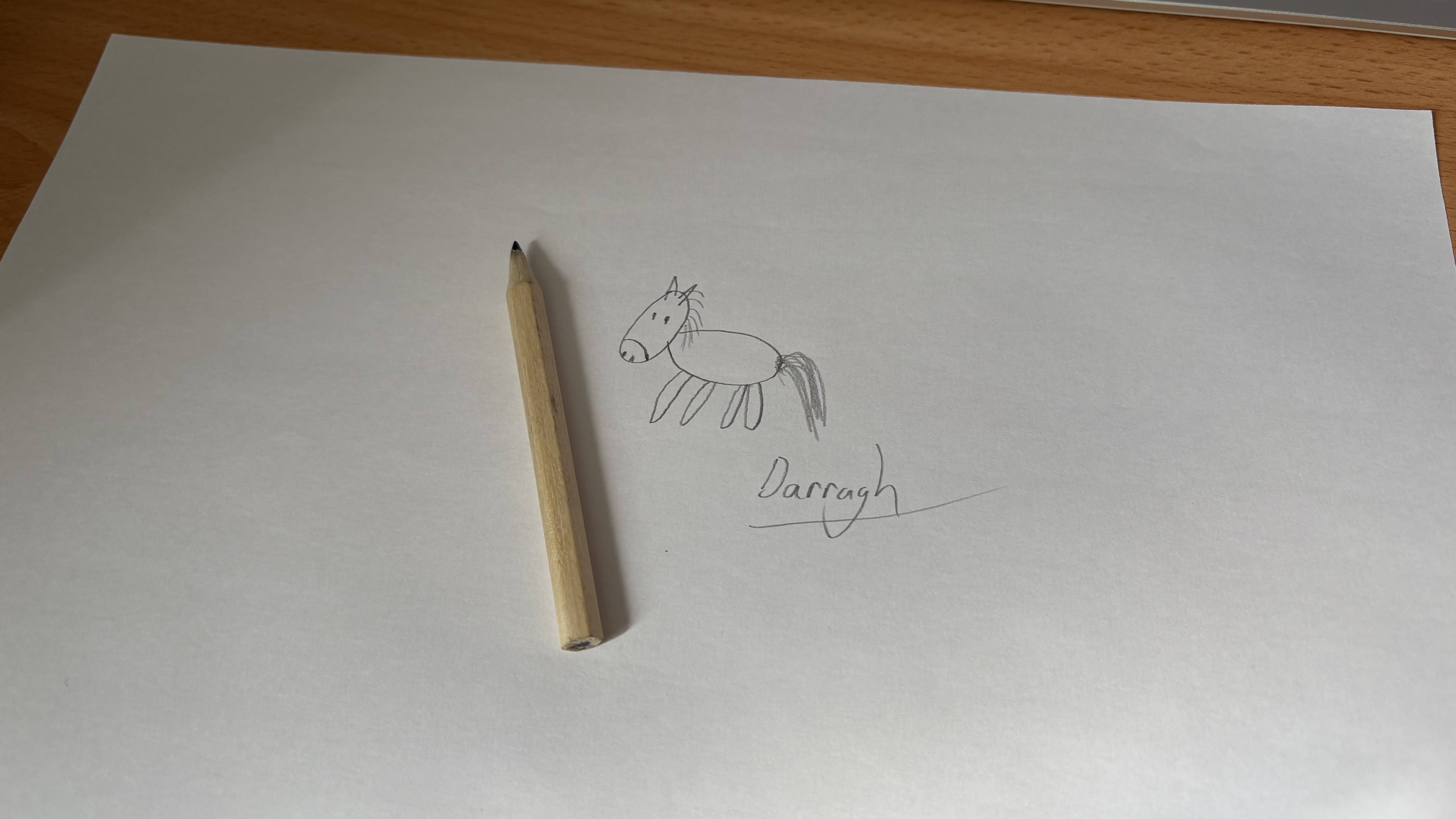 Drawing of cartoon horse on white paper with pencil lying next to it