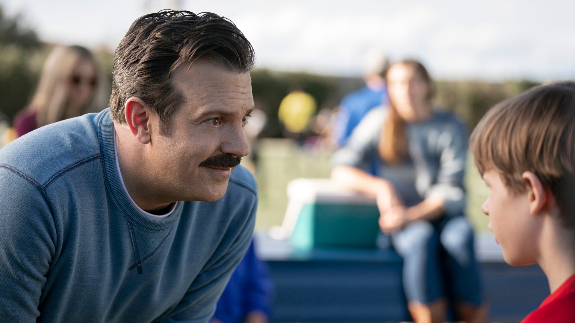 Ted Lasso smiles at a young boy in Ted Lasso