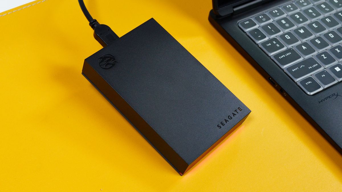 A Seagate FireCuda external gaming hard drive on a desk with a gaming laptop