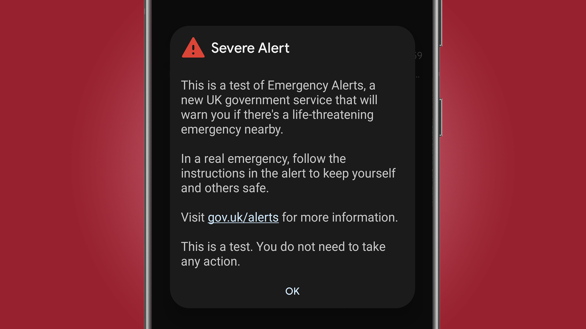 A mobile phone on a red background showing the UK emergency alert test message