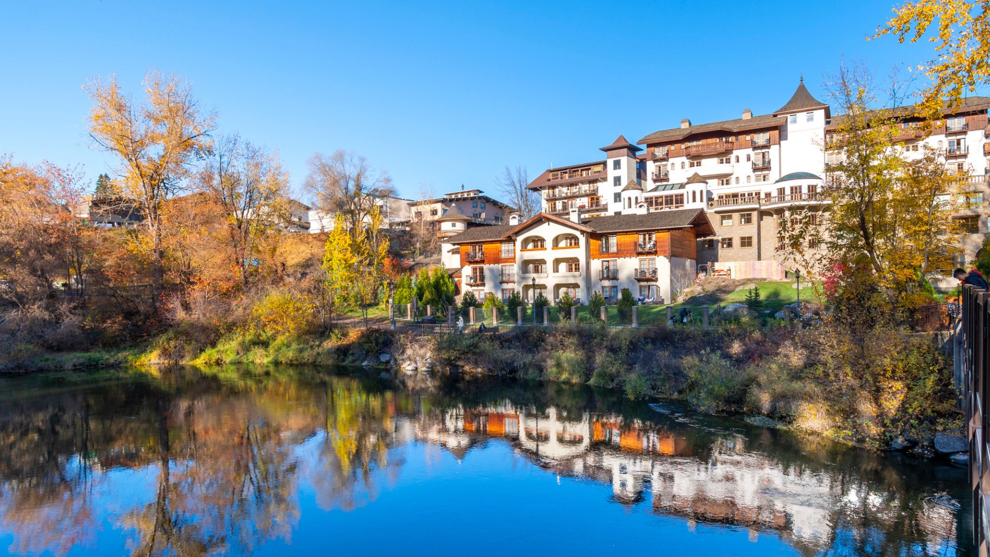 View of the Wenatchee River at autumn with fall colors on the leaves as it flows past the Bavarian themed town of Leavenworth