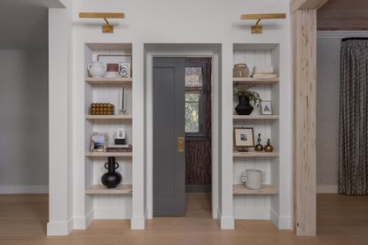 A set of shelves around a doorway decorated with photos, ceramic vases, books and other objet