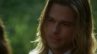 Brad Pitt, wearing long blonde hair, stands under the sun in Legends of the Fall