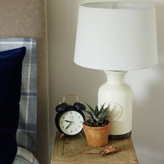 bedroom with white wall and table lamp near alarm watch