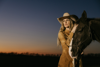 lainey wilson wears a cowboy hat and poses with a horse