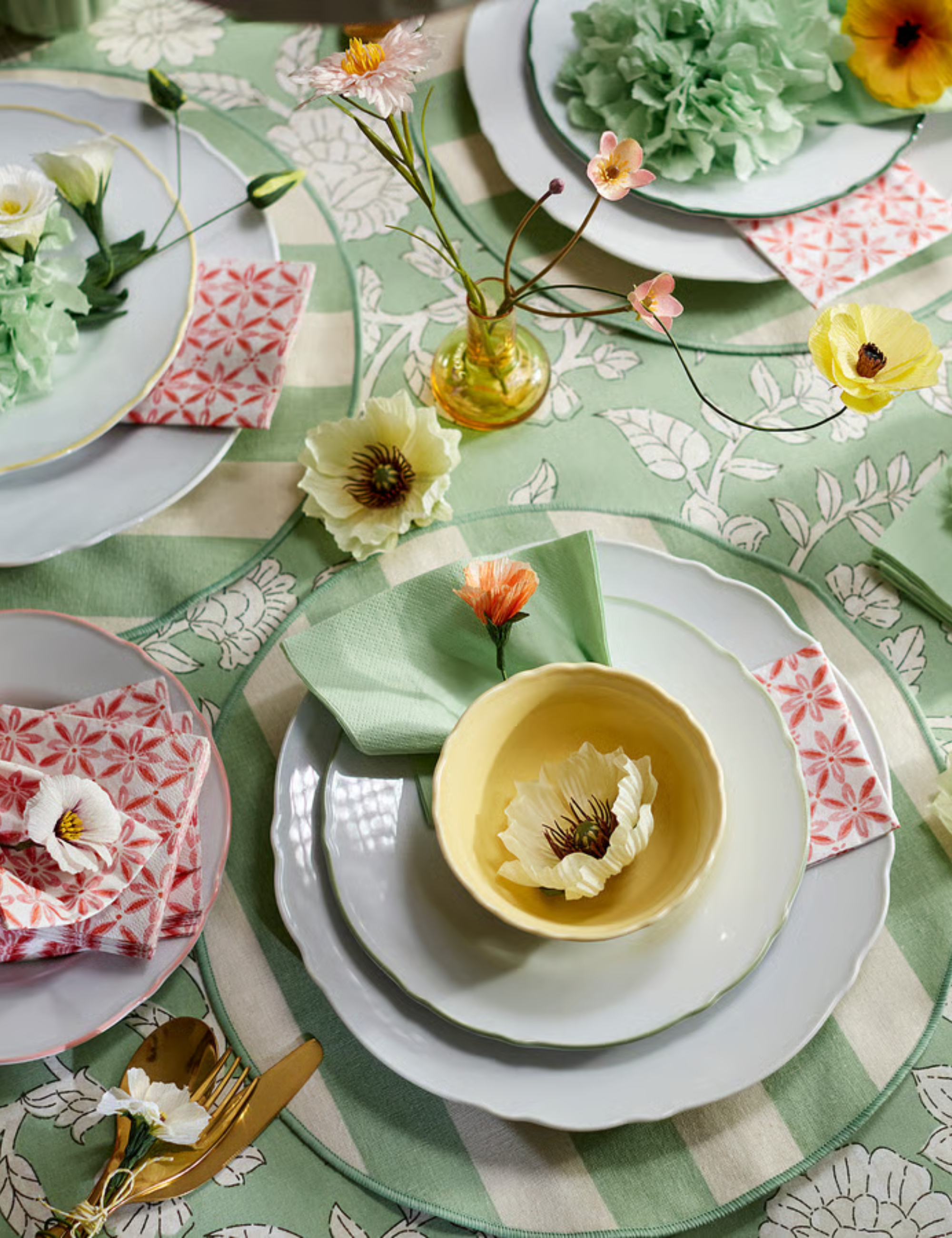 Pastel, pattern-drenched IKEA tablescape featuring striped linen placemats, a floral tablecloth, and antique-inspired plates.
