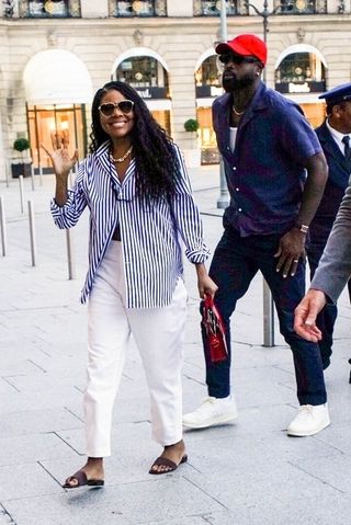 Gabrielle Union enters the Ritz hotel wearing a button down shirt and straight leg jeans with sandals