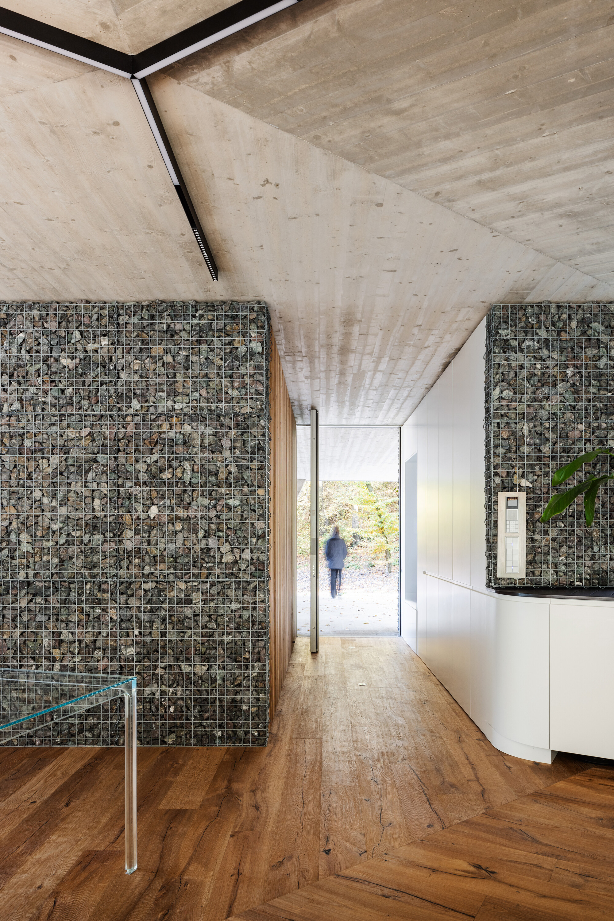 The entrance hall is flanked by gabion walls inside and out
