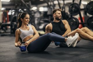 A woman and a man working out in the gym together.