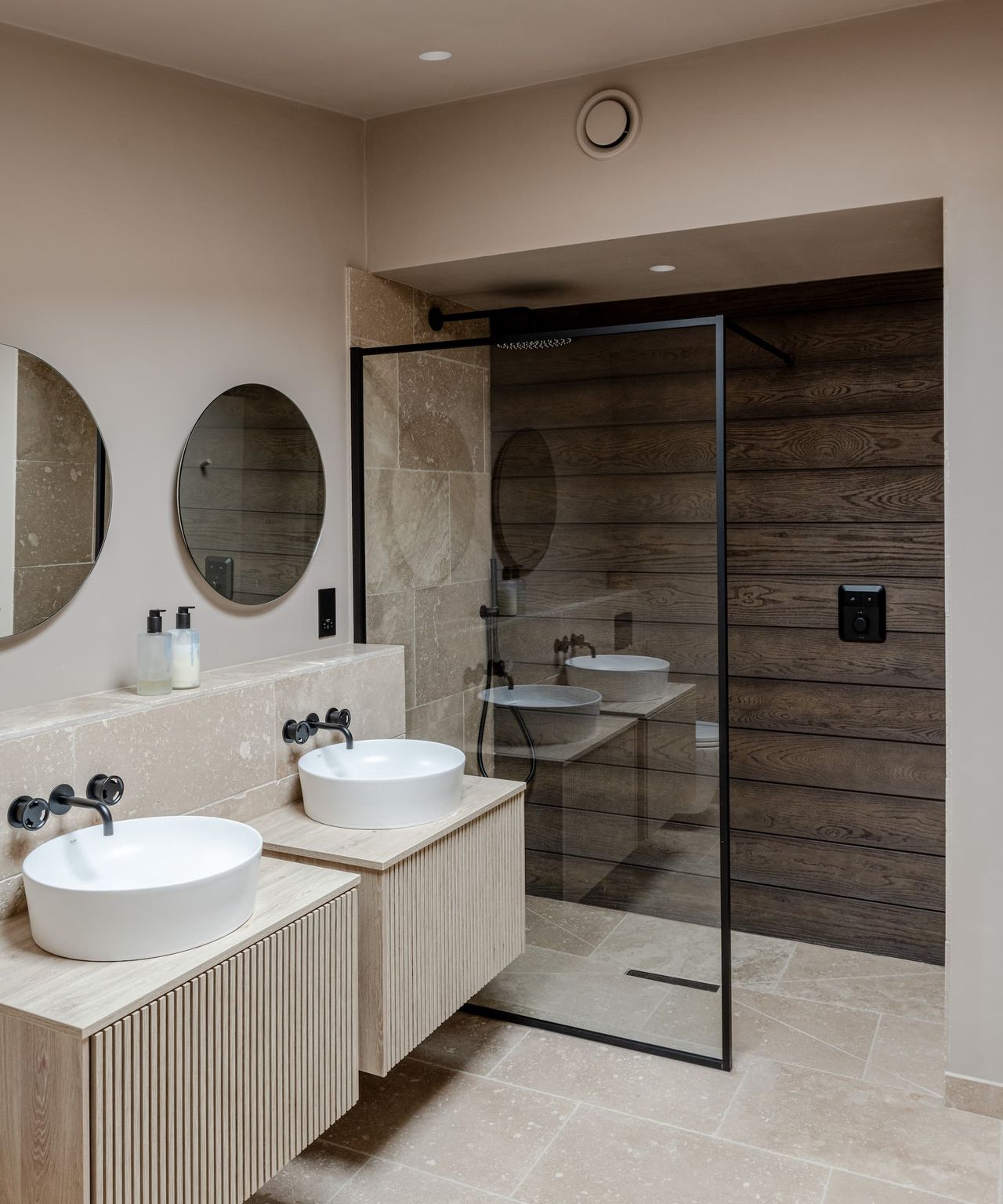 A white bathroom with his and her sinks and a walk in shower