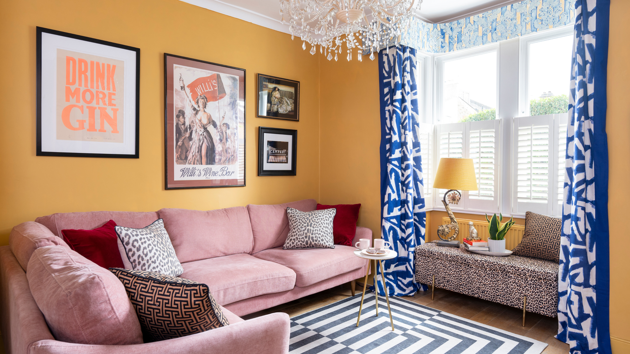 Yellow painted living room with plue curtains and colourful prints.