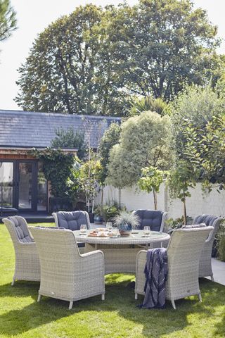 outdoor dining space with small trees growing in garden borders