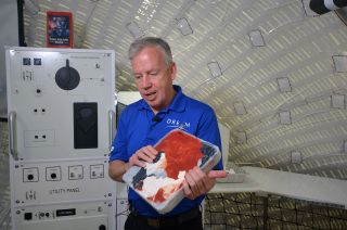 Steve Lindsey, vice president of Sierra Nevada Corp.'s Space Exploration Systems and a former NASA astronaut, shows a compact-trash "brick" that could be used to protect against radiation exposure aboard the company's Large Inflatable Fabric Environment, or LIFE, habitat, part of its Lunar Gateway ground prototype, at NASA's Johnson Space Center in Houston on Aug. 21, 2019.