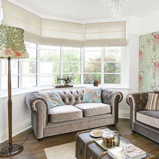 living room with glass window and floor lamp with stitching machine and sofa with cushions