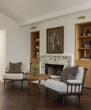 sitting area with cream walls, fireplace, cream armchairs and herringbone floor