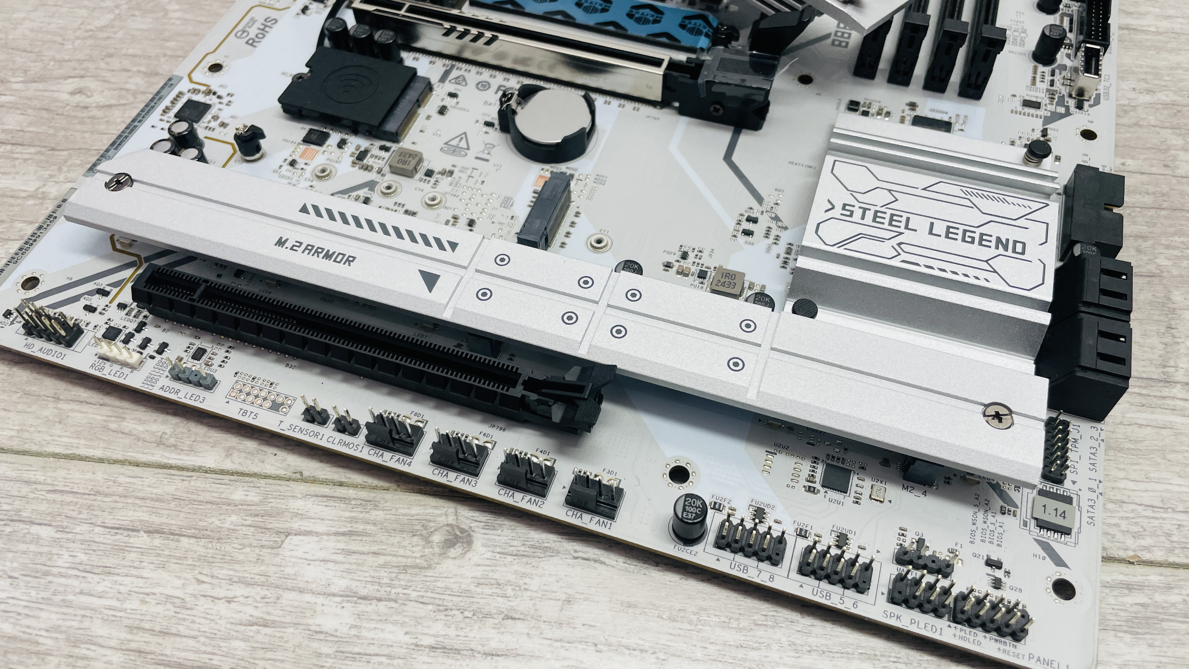 An ASRock B860 Steel Legend Wi-Fi motherboard on a desk with SSD covers removed.