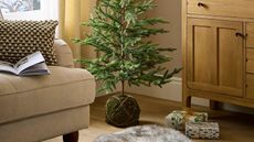 Christmas tree with a kokedama moss ball base in the corner of a beige living room.
