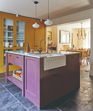 purple cabinetry in kitchen island with yellow cabinetry in background and stone flooring in georgian period home