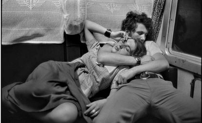 a black and white photograph of a women sleeping in a man's arms