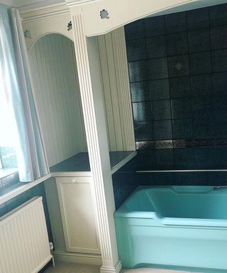 an old fashioned bathroom with a blue tub and white fixtures, and multi-colored curtains