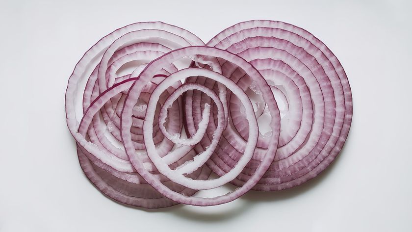 A photo of thinly sliced red onion on a white background