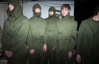 Four models stood in green boiler suits