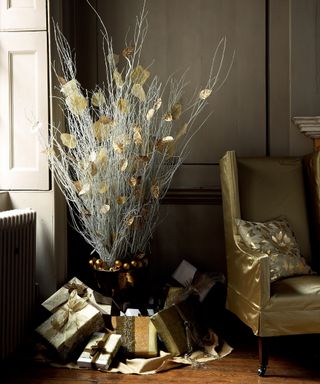 Alternative Christmas tree ideas with a bunch of silver twigs displayed in a vase and decorated with gold leaves