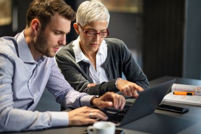 Senior businesswoman cooperating with her male colleague while working on a computer in the office.