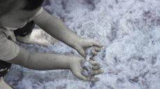 Photo collage of a little boy playing in sand superimposed over a closeup picture of asbestos fibres