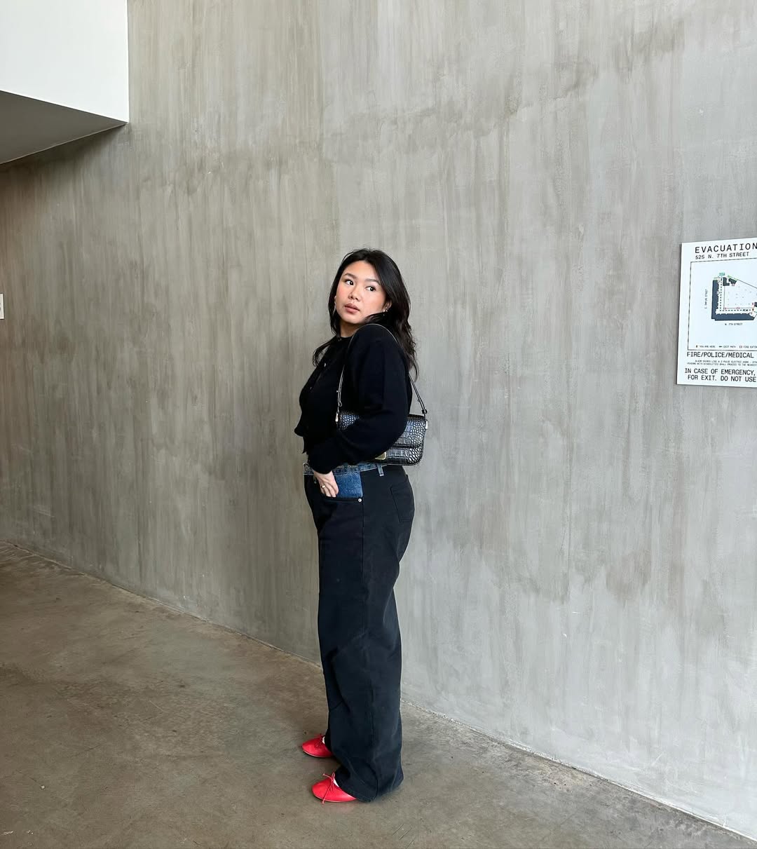 @marina_torres wears a black cardigan, black jeans, red pumps and a shoulder bag