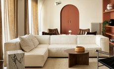 A living room with beige walls, sofa and terracotta-painted door