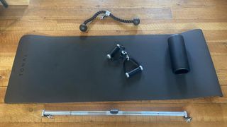 The Tonal workout equipment components, including a roller, mat and rope