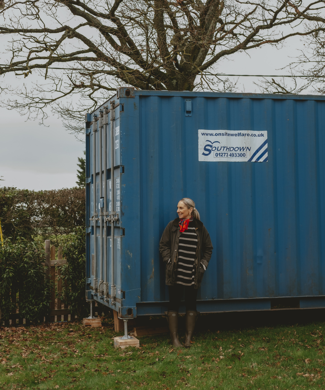 Abbie standing outside the blue shipping container before it was renovated